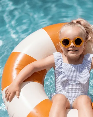 Kind in Schwimmreifen im beschatteten Kinderbecken im Freibad Mirador