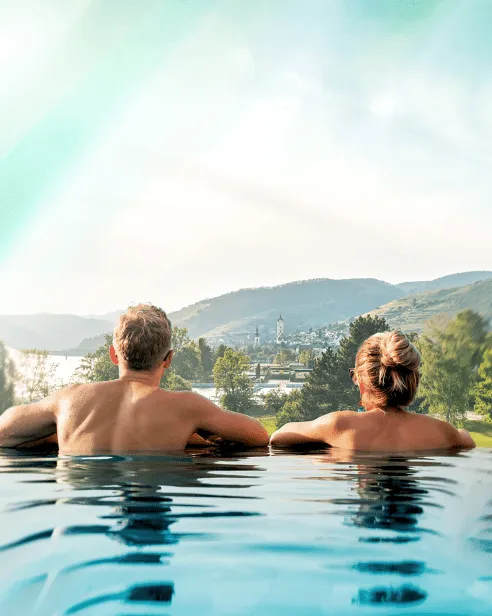 Paar genießt Aussicht im Infinity-Pool über die Wachau und die Donau
